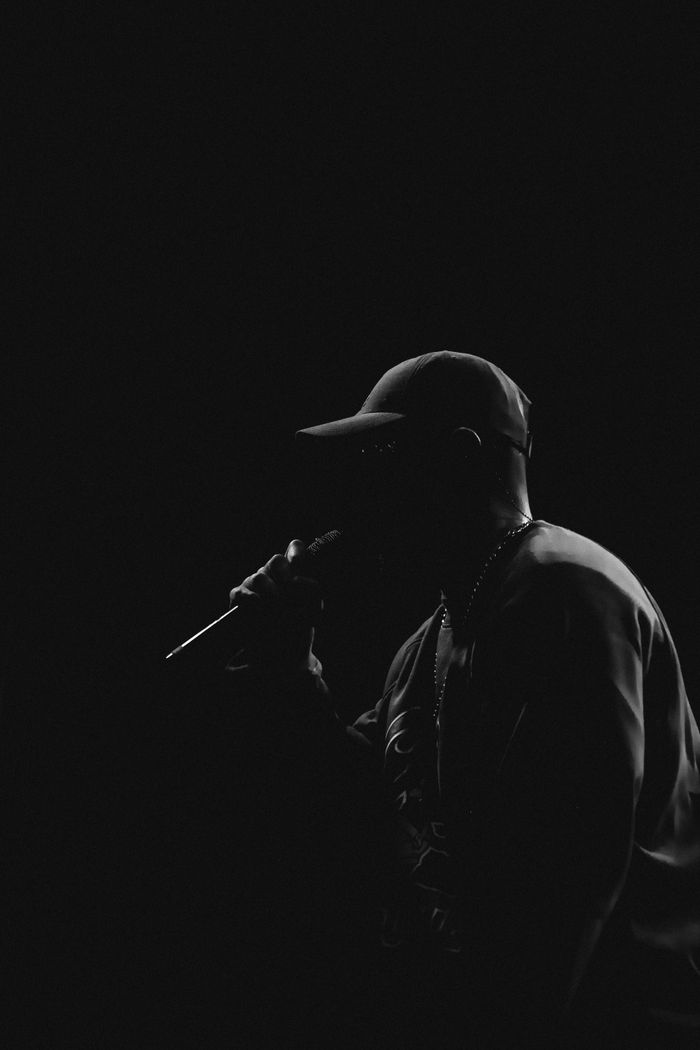 A dramatic black and white silhouette of a male singer performing on stage with a microphone.