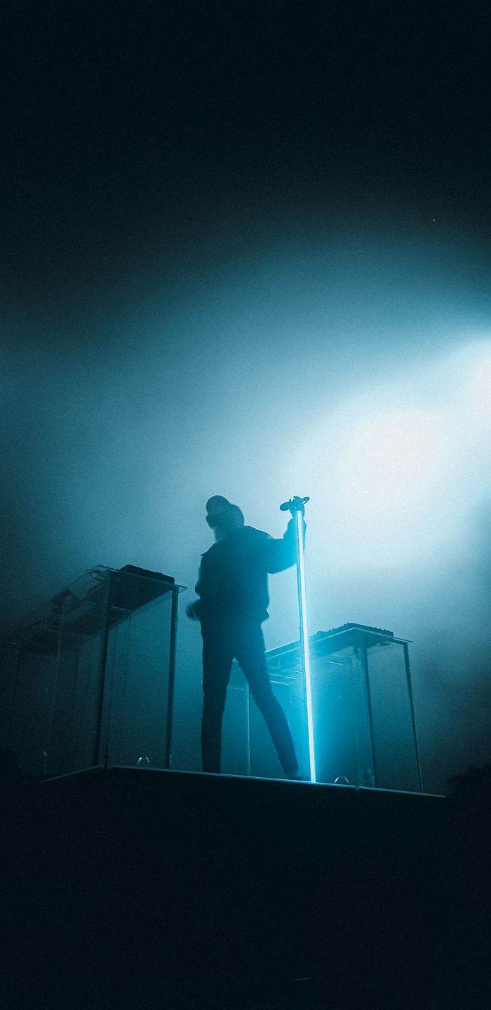 services-01 A musician stands silhouetted on stage with dramatic lighting, creating a captivating scene.